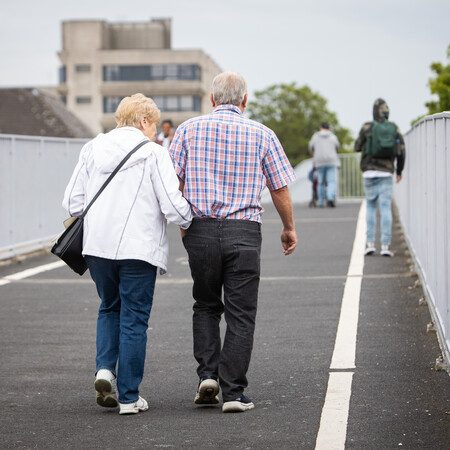 Two people walking over a pedestrian bridge.