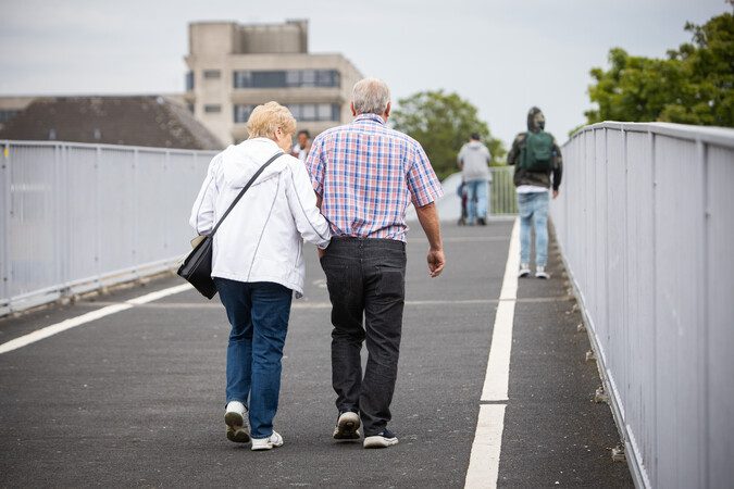 Two people walking over a pedestrian bridge.